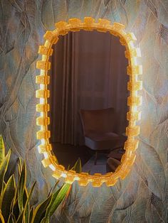 a mirror that is on the side of a wall next to some plants and a chair