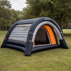 an inflatable tent is set up on the grass with trees in the background