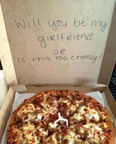 a pizza sitting inside of a box on top of a wooden table next to a sign