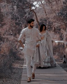 a man and woman dressed in white walking down a path