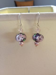 The one of a kind earrings feature a gorgeous purple lampwork bead with pink flowers, complimented by a light pink glass bead, pink Swarovski crystal pearl and sterling silver disc-shaped spacer bead on a sterling silver earring wire.   To see my other earrings: https://www.etsy.com/ca/shop/SimpleEleganceByJ?ref=condensed_trust_header_title_sold&section_id=20163243 To check out the rest of my shop: https://www.etsy.com/ca/shop/SimpleEleganceByJ Thanks for stopping by! Elegant Pink Czech Glass Earrings, Pink Flower Glass Jewelry, Pink Flower-shaped Glass Jewelry, Pink Beaded Pearl Drop Earrings For Gift, Pink Pearl Drop Beaded Earrings For Gifts, Pink Sterling Silver Beaded Earrings Gift, Pink Glass Round Jewelry, Pink Round Glass Jewelry, Elegant Pink Beaded Sterling Silver Earrings