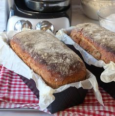 two loafs of bread sitting on top of a red and white checkered cloth