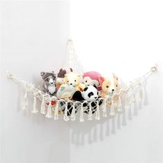 a hammock filled with stuffed animals on top of a white wall and hanging from it's sides