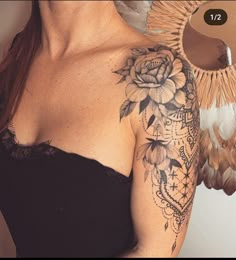 a woman with a flower tattoo on her arm and shoulder next to a feather fan