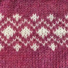 a close up of a knitted sweater with white and pink designs on the side