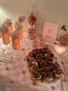 a table topped with lots of food next to wine bottles and glasses filled with liquid