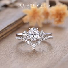 a close up of a diamond ring on a wooden surface with flowers in the background