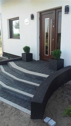 a house with steps leading up to the front door and potted plants on either side