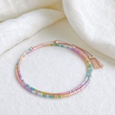 Our Shimmer Rainbow bracelet is made to catch the light when you move with rainbow coloured glass beads and silver sliding clasp to adjust length.  The silk cord is a pale pink colour and the beads are high quality glass beads in pink, peach, yellow, green, pale blue and lilac. Fits an average wrist size of up to 7 inches and tightens to 6.25in. Extends to maximum of 8.5in to fit over the widest part of the hand. If you have a small wrist and hands and would like a smaller bracelet size please contact me. Displayed in one of our pretty gift boxes, so fantastic as a present for a friend or to yourself! Check out the matching necklace https://www.etsy.com/uk/listing/1279385760/beaded-shimmer-rainbow-necklace-dainty Shipping Uk: 2-3 days - Royal Mail 48hr tracked International standard delive Colorful Adjustable Round Bead Bracelets, Colorful Adjustable Bracelets With Round Beads, Rainbow Sliding Knot Bracelets For Friendship, Rainbow Sliding Knot Bracelet For Friendship, Adjustable Colorful Hand-strung Bracelets, Colorful Adjustable Hand-strung Beaded Bracelets, Rainbow Sliding Knot Friendship Bracelet, Adjustable Rainbow Friendship Bracelets With Colorful Beads, Adjustable Rainbow Friendship Bracelet With Colorful Beads