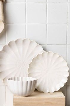 two white dishes sitting on top of a wooden shelf