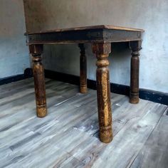 an old wooden table sitting on top of a hard wood floor next to a wall