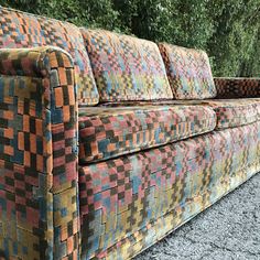 a multicolored couch sitting on top of gravel