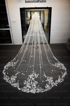 a white wedding veil with flowers on the bottom is hanging in front of a doorway