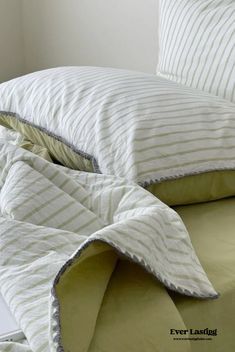 an unmade bed with white and green sheets