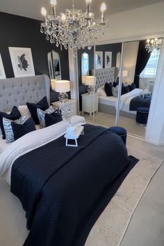 a bedroom with black and white bedding, chandelier and mirror on the wall