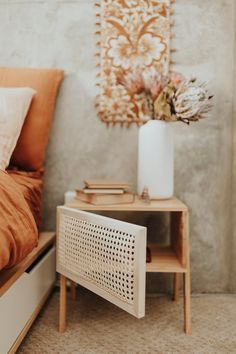 a bedroom with a bed, nightstand and vase on the side table next to it