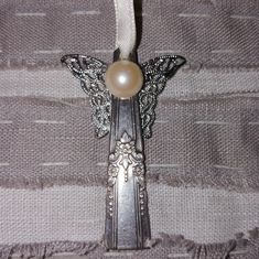 a piece of silverware with a butterfly decoration on it's side and a pearl bead in the middle