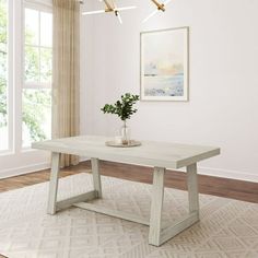 a white table with a plant on top in front of a window and a rug