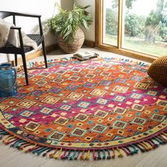 a brightly colored rug with fringes on the floor next to a chair and potted plant