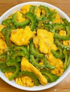 a white bowl filled with green peppers and cauliflower on top of a wooden table