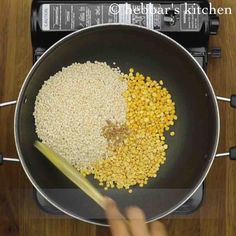 someone cooking corn in a frying pan on top of an electric stove with a wooden spatula