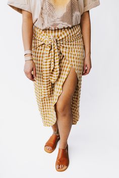 Liven up your wardrobe with The Yancy Gingham Skirt! A playful knot tie creates a fun and unique look with classic gingham pattern. Flaunt your style and show off your mustard and white duo with this must-have skirt! size up Details Model is wearing a small self/lining: 55% rayon + 43% polyester + 2% spandex Fabric Care Guide Here Sizing & Fit Measurements are approximate and taken while laying flat across the front. Not doubled. small: waist = 13"; length = 34" medium: waist = 13.5"; length = 3