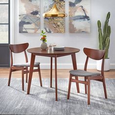 a small table with two chairs and a potted plant in front of the wall