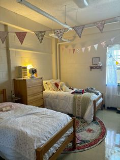 two twin beds in a room with bunting flags on the ceiling and rugs