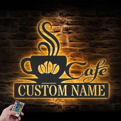 a person holding a cell phone in front of a sign that says cafe custom name