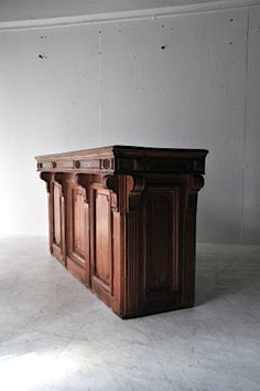 an empty room with a large wooden table in the center and white walls behind it