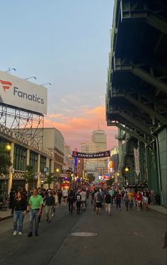 many people are walking down the street in front of an electronic sign that reads fanaticss