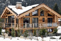 a large wooden house with snow on the roof and balconies in front of it