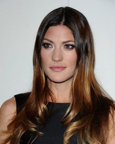 a woman with long brown hair posing for the camera