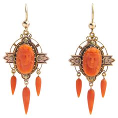 This pair of 18 karat gold and coral drop earrings are High Victorian in terms of their age and appearance and are a beautiful example of 19th century craftsmanship. The pair each centre on an oval cameo of a woman carved from natural coral which has been framed in an elaborate 18 karat gold setting that has been oxidised in areas to bring out the brightness of the gold. To the bottom of the cameo medallions hang three carved coral drops which sway with the movement of the wearer. To affix to th Carved Yellow Gold Earrings For Formal Occasions, Formal Carved Yellow Gold Earrings, Victorian Cameo Yellow Gold Earrings, Formal Carved Earrings, Elegant Carved Orange Jewelry, Elegant Orange Carved Jewelry, Coral Drop Earrings, Victorian Earrings, Shepherds Hook