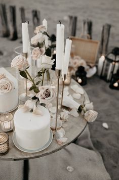 a table topped with two white cakes and candles next to other items on the ground