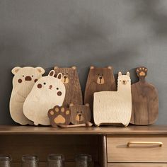 wooden bears are sitting on top of a shelf next to glasses and cups, with one bear in the middle