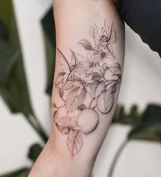 a woman's arm with flowers and apples tattooed on the left side of her arm