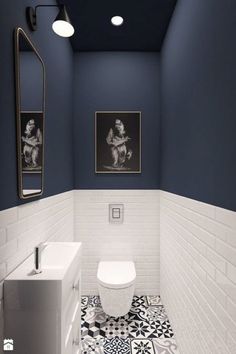 a white toilet sitting next to a sink in a bathroom under two pictures on the wall