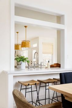 an open kitchen and dining room with bar stools in the foreground, looking into the breakfast nook