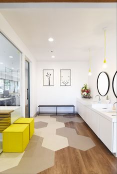 a bathroom with two sinks and yellow stools