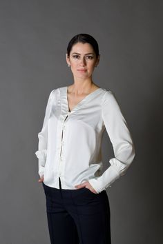 "A beautiful satin blouse featuring button front closure, long sleeves with cuffs, and a v-neckline. - v-neckline - fabric button front closure - long sleeves with cufffs - shift silhouette Color: white (milky-white) Fabric: Viscose - 30, polyester - 65%, elastane - 5%. Our model wears size US 8 and is 171cm/5'6\" tall. You may feel free choosing the size. Just send us your measurements (bust, waist, hips, height). SIZE CHART XS __ EU 34 __ US 4 bust: 31,5\" | 80 cm waist: 24,5\" | 62 cm hips: 3 Satin V-neck Top For Office, Elegant V-neck Blouse For Fall, Fitted V-neck Shirt With Button Cuffs, Silk V-neck Blouse With Button Closure, Fall V-neck Blouse With Buttons, Elegant V-neck Shirt With Back Button Closure, Elegant V-neck Top With Button Cuffs, Elegant V-neck Blouse For Office, Satin Long Sleeve Top For Office