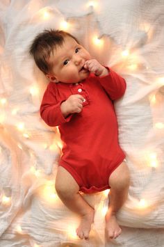 a baby laying on top of a bed with lights around it's head and body