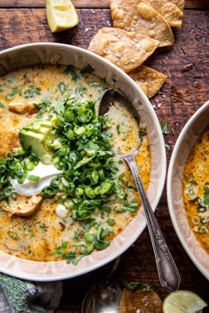 two bowls of soup with tortilla chips and avocado on the side