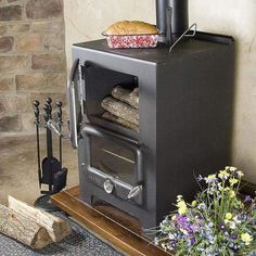 a black stove sitting on top of a wooden table next to flowers and potted plants