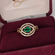 This beautiful east west ring features a vibrant green emerald in 14k yellow gold with a pave diamond double halo in a unique design. Green Emerald Diamond Ring With Pave Setting, Green Emerald Ring With Pave Setting, Green Emerald Diamond Ring With Halo, Formal Green Cluster Ring With Halo, Formal Green Halo Cluster Ring, Green Emerald Ring With Diamond Halo, Green Emerald Ring With Halo Diamond Design, Green Emerald Ring With Pave Setting For May Birthstone, Green Emerald Ring With Halo Diamond