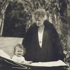 an old black and white photo of a woman with a baby in a stroller