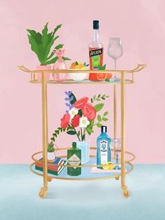 a gold bar cart with drinks and flowers on the top is against a pink wall