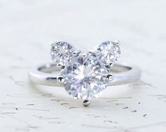 a heart shaped diamond ring sitting on top of a table