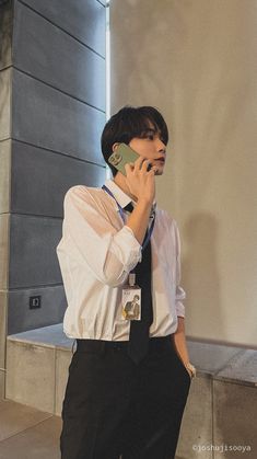 a young man talking on a cell phone while wearing a neck tie and suspenders