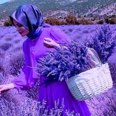 a woman in a purple dress holding a wicker basket and walking through lavender fields